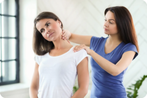 Eine Physiotherapeutin massiert eine andere Frau im Nacken.