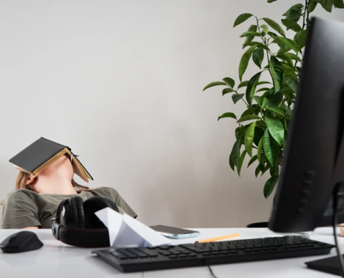 Person hängt auf Bürostuhl und hat ein Buch über ihr Gesicht gelegt.