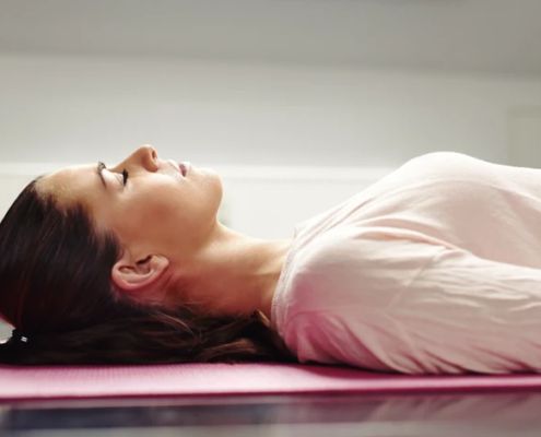 Frau liegt entspannt auf Yoga-Matte.