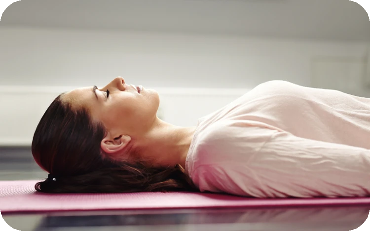 Frau liegt entspannt auf Yoga-Matte.