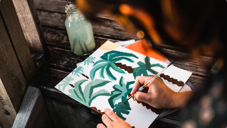 Person malt ein Bild mit Palmen.