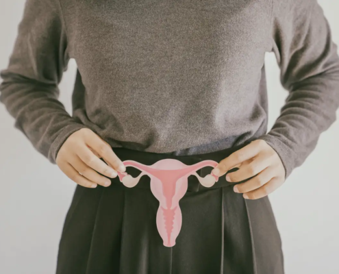 Frau hält Uterus aus Papier vor ihren Unterleib